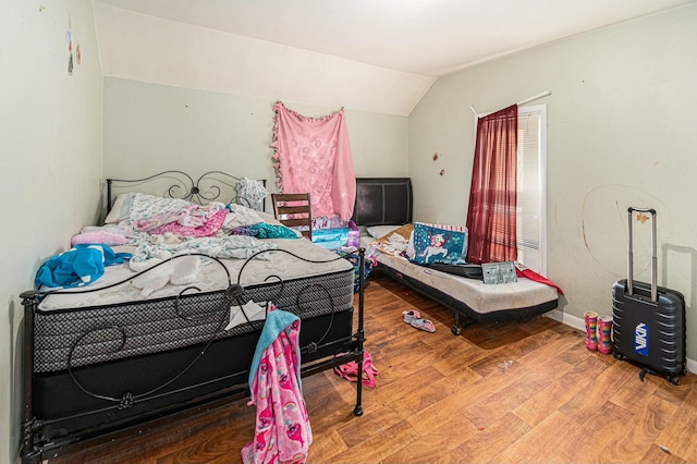 bedroom with baseboards, lofted ceiling, and wood finished floors