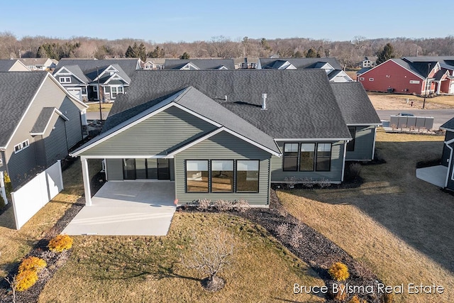 view of front of property with a carport, a front yard, a residential view, and roof with shingles