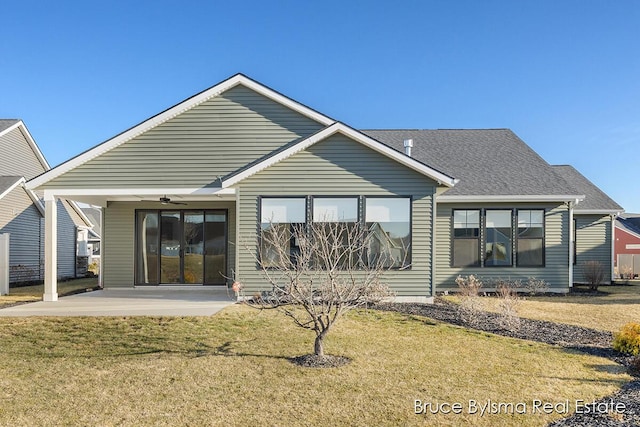 rear view of property featuring a patio, a lawn, ceiling fan, and a shingled roof