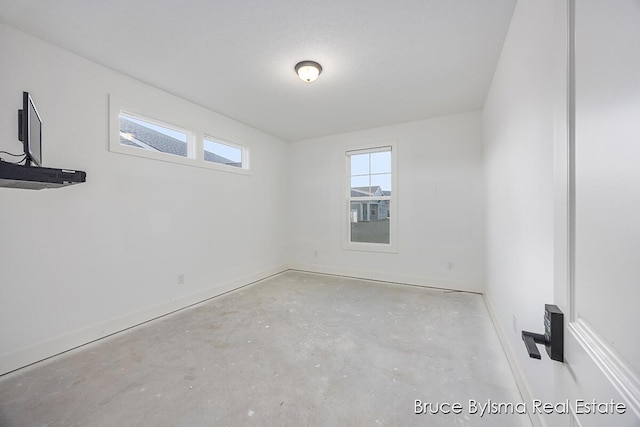 unfurnished room featuring unfinished concrete floors and baseboards