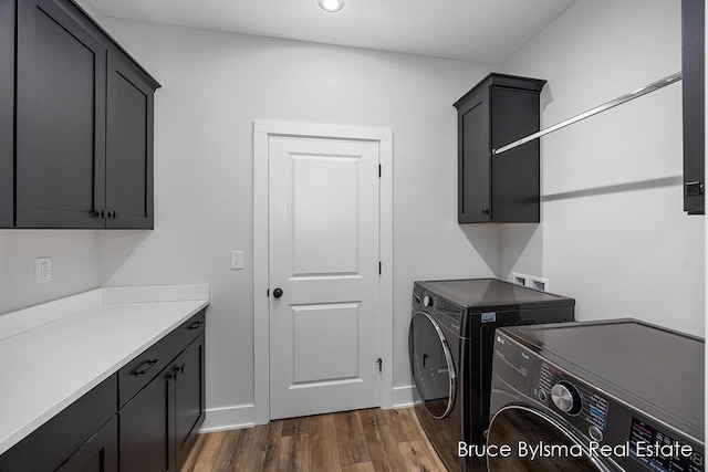 laundry room featuring dark wood-style floors, cabinet space, washer and dryer, and baseboards