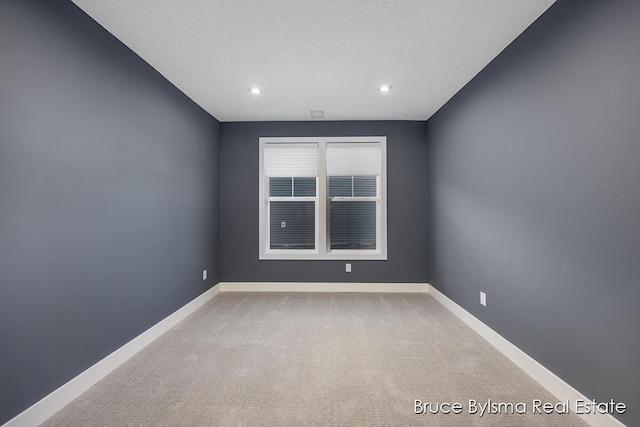 carpeted empty room with recessed lighting, baseboards, and a textured ceiling