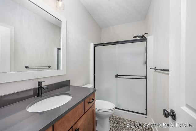 bathroom with a stall shower, toilet, vanity, and a textured ceiling