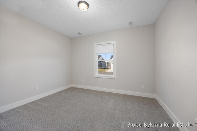 carpeted empty room featuring visible vents, a textured ceiling, and baseboards