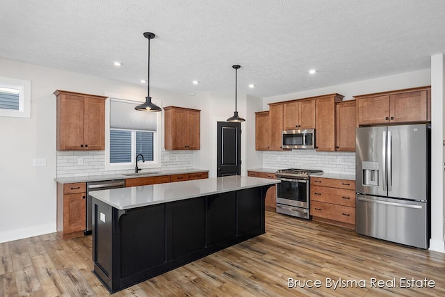 kitchen featuring a sink, appliances with stainless steel finishes, a center island, and brown cabinetry