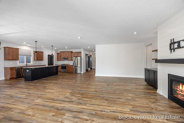 living room featuring dark wood-style floors, a glass covered fireplace, recessed lighting, and a textured ceiling