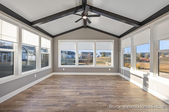 unfurnished sunroom featuring a healthy amount of sunlight, lofted ceiling with beams, and a ceiling fan