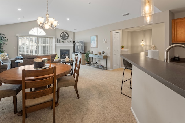 dining space with visible vents, a notable chandelier, a glass covered fireplace, lofted ceiling, and light colored carpet