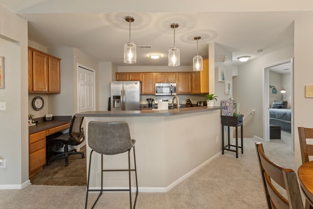 kitchen with stainless steel appliances, a peninsula, a breakfast bar area, and built in study area