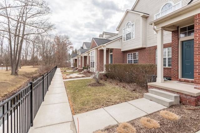 view of side of home with fence, brick siding, and a residential view