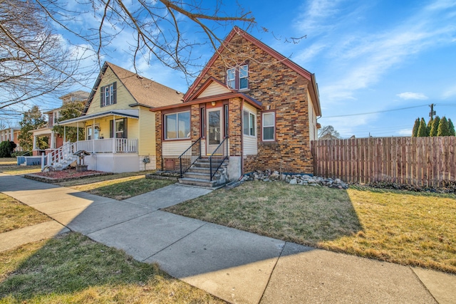 bungalow-style house featuring brick siding, a porch, a front yard, and fence