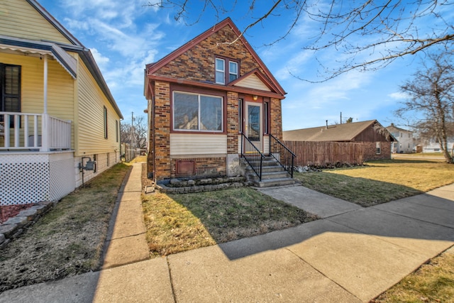 view of front of house with brick siding, a front yard, and fence