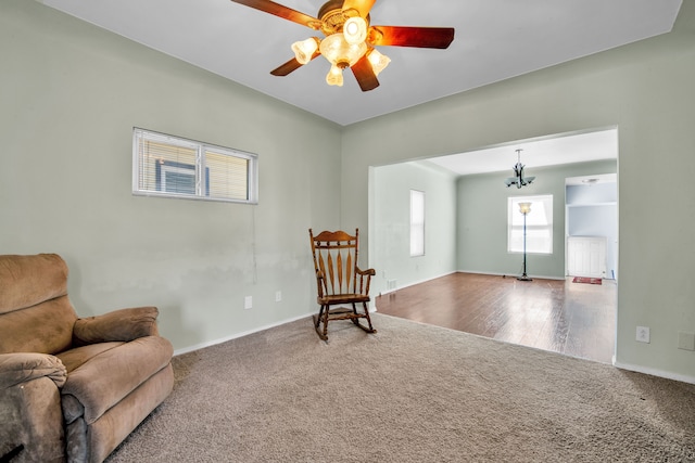 living area featuring carpet flooring, baseboards, and a ceiling fan