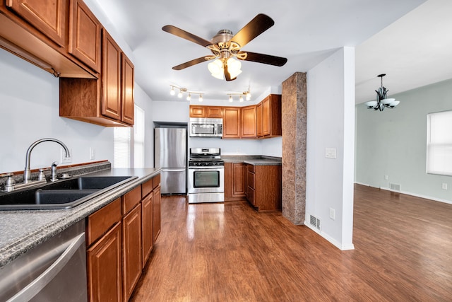 kitchen with visible vents, dark wood-type flooring, brown cabinets, stainless steel appliances, and a sink