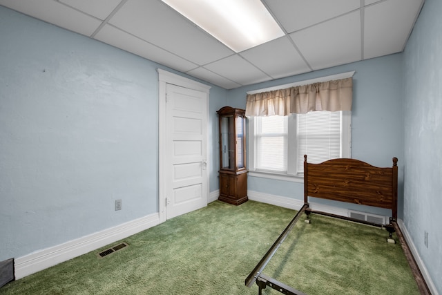 carpeted bedroom with a drop ceiling, baseboards, and visible vents