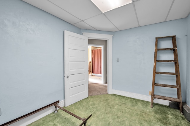 carpeted spare room featuring a paneled ceiling and baseboards