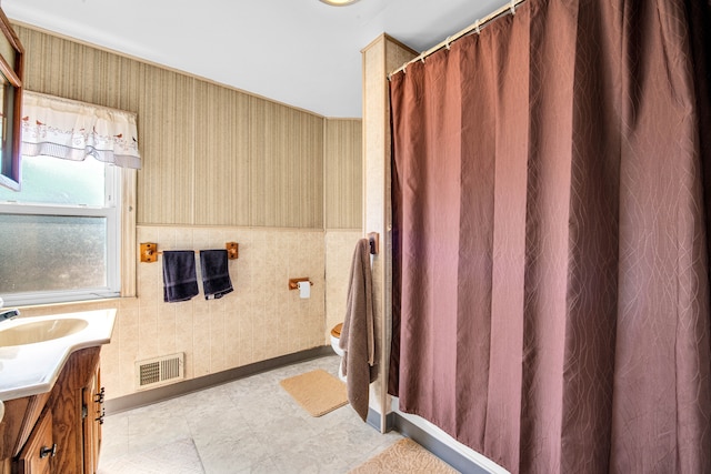 full bathroom featuring vanity, visible vents, wallpapered walls, wainscoting, and toilet