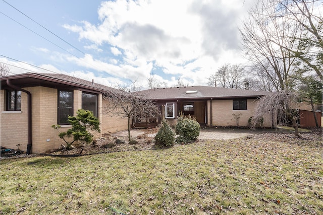 rear view of house featuring brick siding, a yard, and a patio