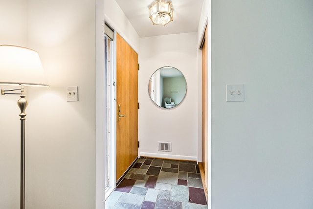 corridor with stone finish floor, visible vents, and baseboards