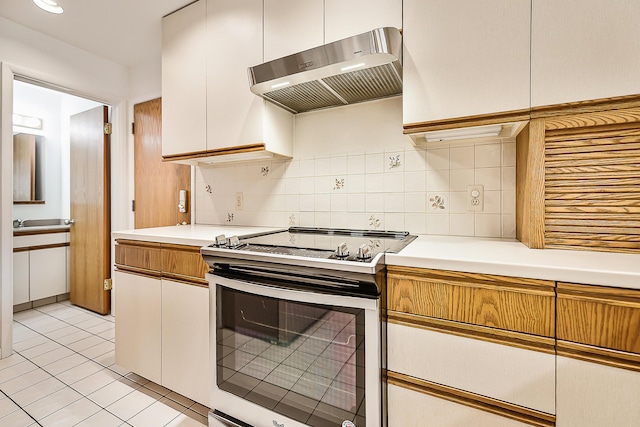 kitchen featuring under cabinet range hood, tasteful backsplash, stainless steel electric stove, light countertops, and light tile patterned floors