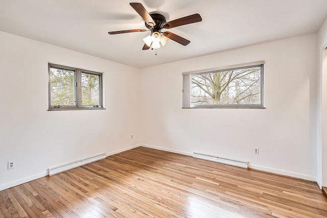 spare room featuring a baseboard heating unit, plenty of natural light, and light wood-type flooring