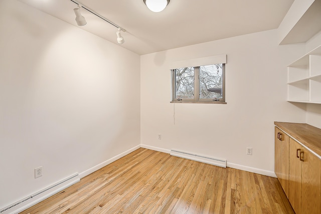 empty room with baseboards, light wood-type flooring, baseboard heating, and a baseboard radiator