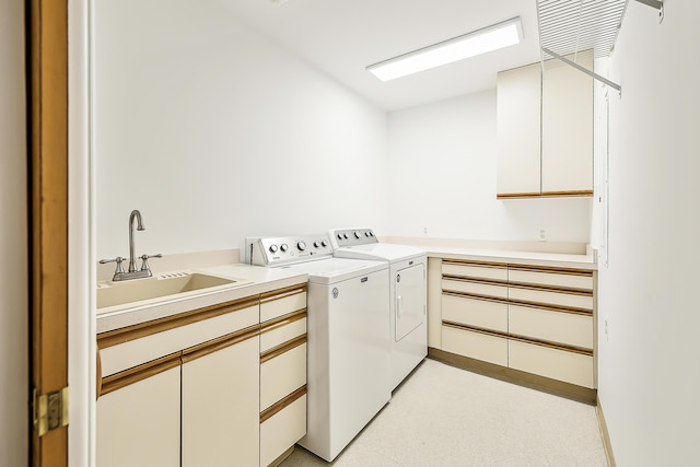 washroom with cabinet space, washer and dryer, and a sink