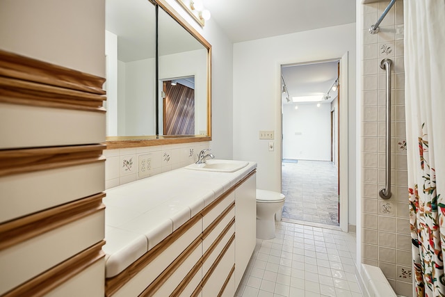 bathroom with toilet, decorative backsplash, tiled shower, tile patterned floors, and vanity