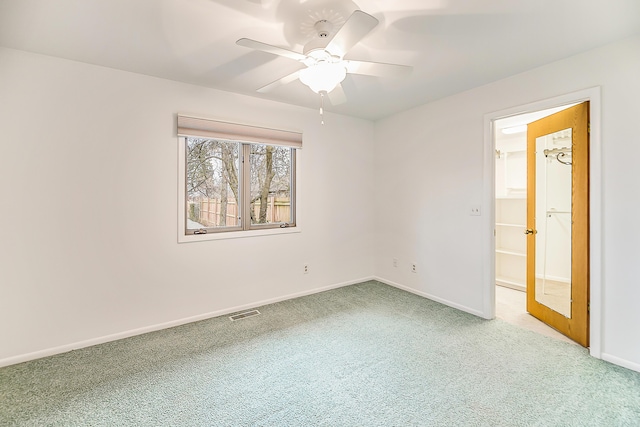 carpeted empty room with visible vents, baseboards, and a ceiling fan