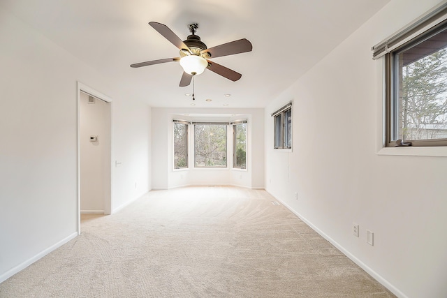 carpeted empty room with ceiling fan and baseboards