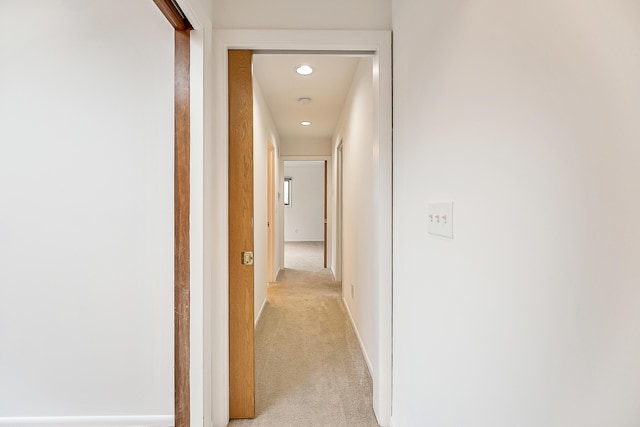 hallway with light colored carpet and baseboards