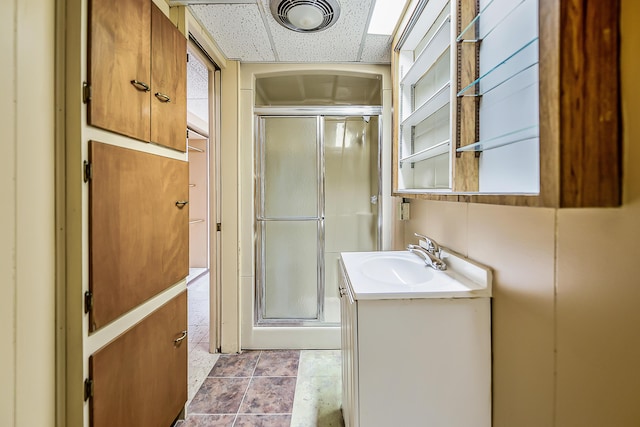 bathroom with vanity, a shower stall, tile patterned floors, and a drop ceiling