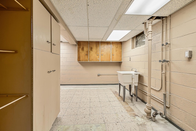 bathroom featuring tile patterned floors, concrete block wall, and a paneled ceiling