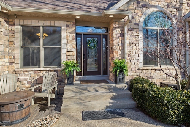 entrance to property with stone siding and roof with shingles