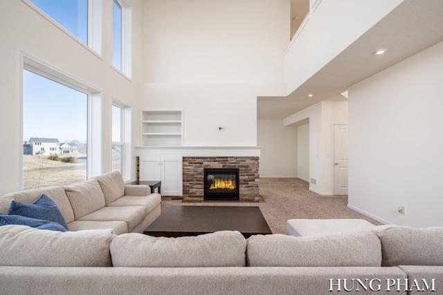 living area with built in shelves, baseboards, a fireplace with flush hearth, recessed lighting, and carpet flooring