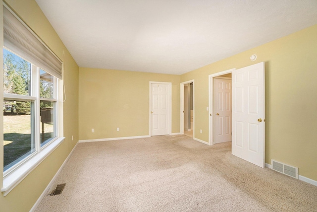 spare room with light carpet, visible vents, and baseboards