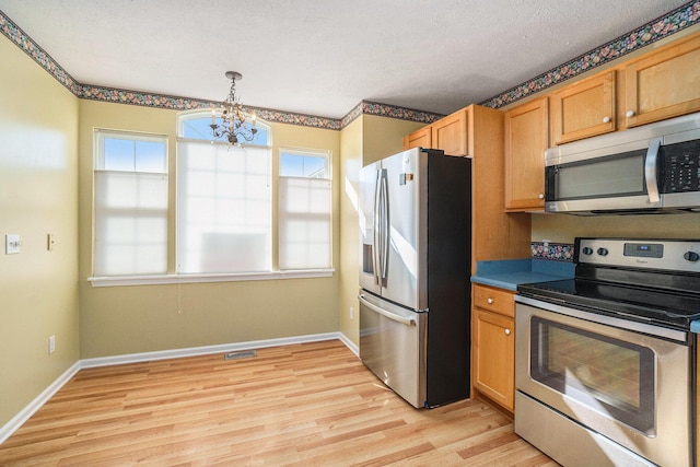 kitchen featuring light wood finished floors, baseboards, appliances with stainless steel finishes, an inviting chandelier, and a textured ceiling