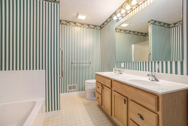 bathroom with a textured ceiling, wallpapered walls, and a sink