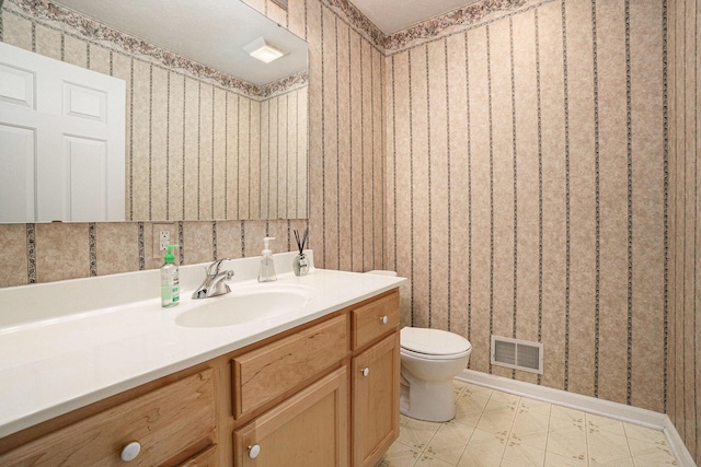 bathroom with vanity, visible vents, wallpapered walls, tile patterned floors, and toilet