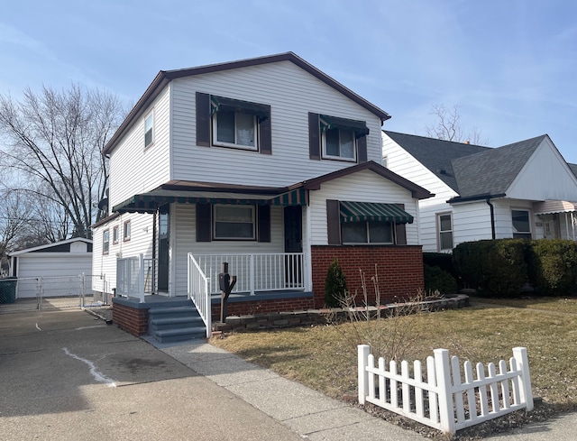 view of front facade featuring an outdoor structure, covered porch, fence, and brick siding