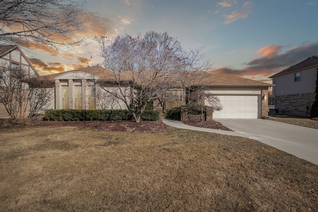 view of front of house with brick siding, an attached garage, concrete driveway, and a yard