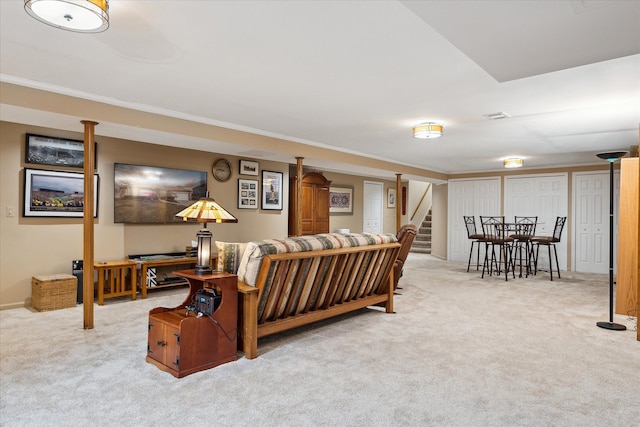 carpeted living area with stairway, visible vents, and ornamental molding