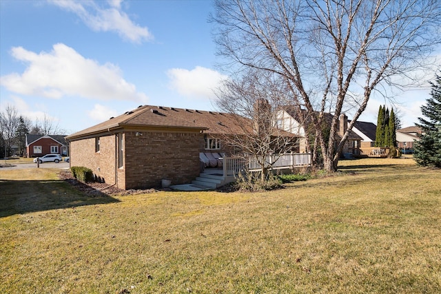 exterior space featuring brick siding, a deck, and a lawn