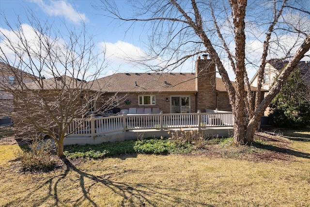 back of property featuring a yard, a deck, and a chimney