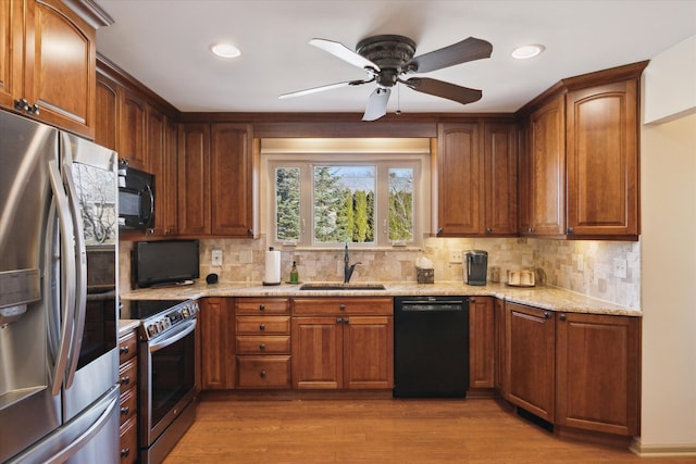 kitchen with light stone counters, wood finished floors, a sink, black appliances, and backsplash