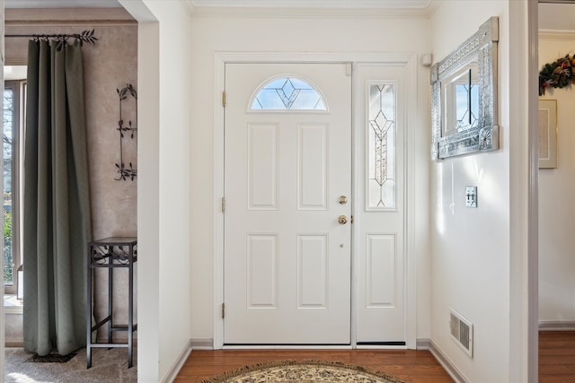 entrance foyer featuring visible vents, baseboards, wood finished floors, and ornamental molding