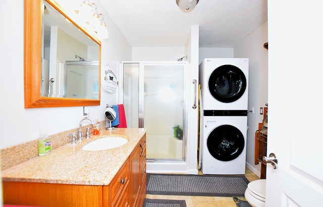 full bathroom with stacked washer / dryer, toilet, a stall shower, and vanity