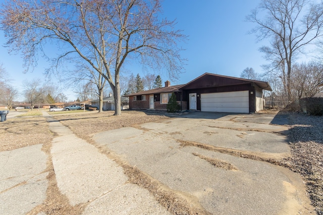 view of front of property featuring a garage, a chimney, and driveway