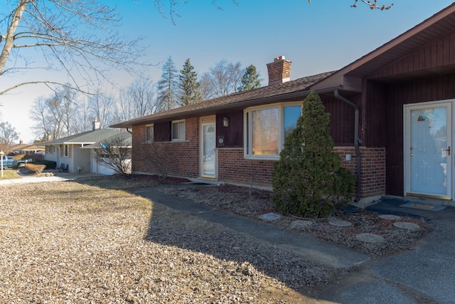 ranch-style house featuring brick siding and a chimney