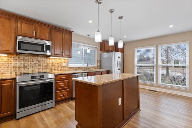 kitchen with a sink, tasteful backsplash, light wood finished floors, and stainless steel appliances